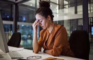 Kada je vreme da date otkaz; umorna žena prdržava prstima čelo u kancelariji na poslu